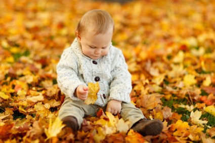 Мальчик сидит в парке осенью