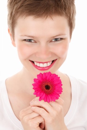 улыбается женщина с цветком