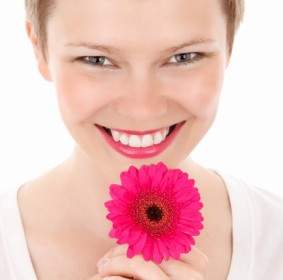 улыбается женщина с цветком